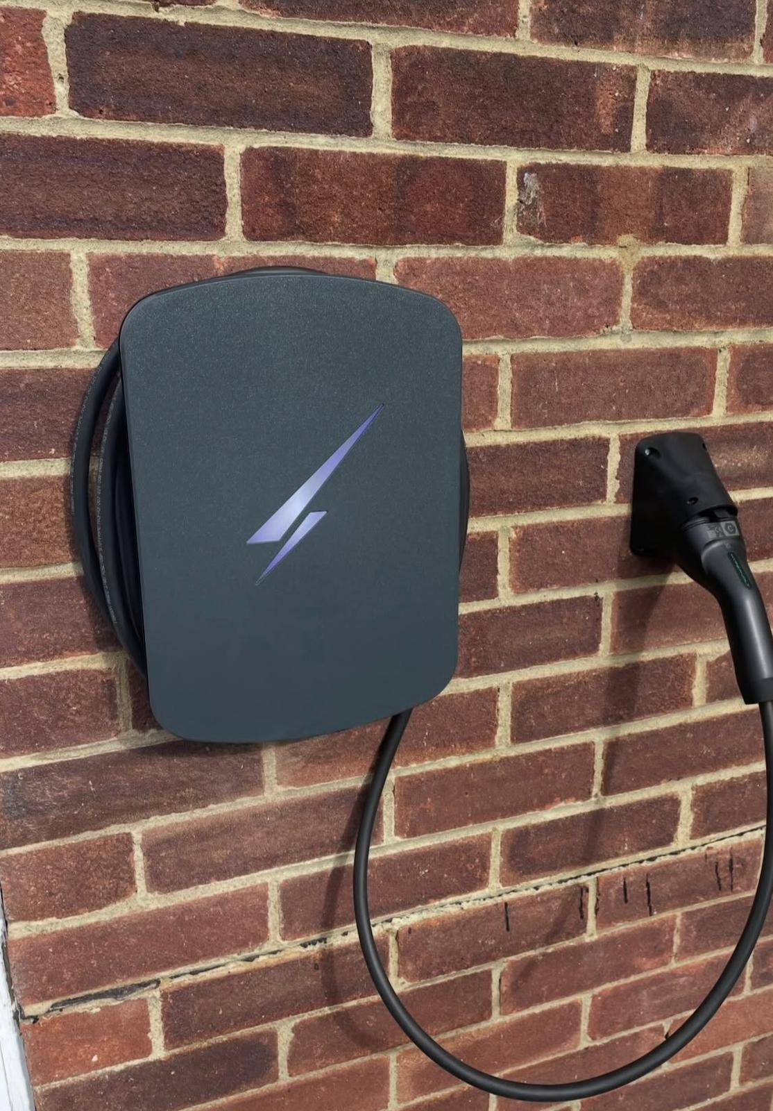 EV charger with lightning bolt logo installed on brick wall in Cobham