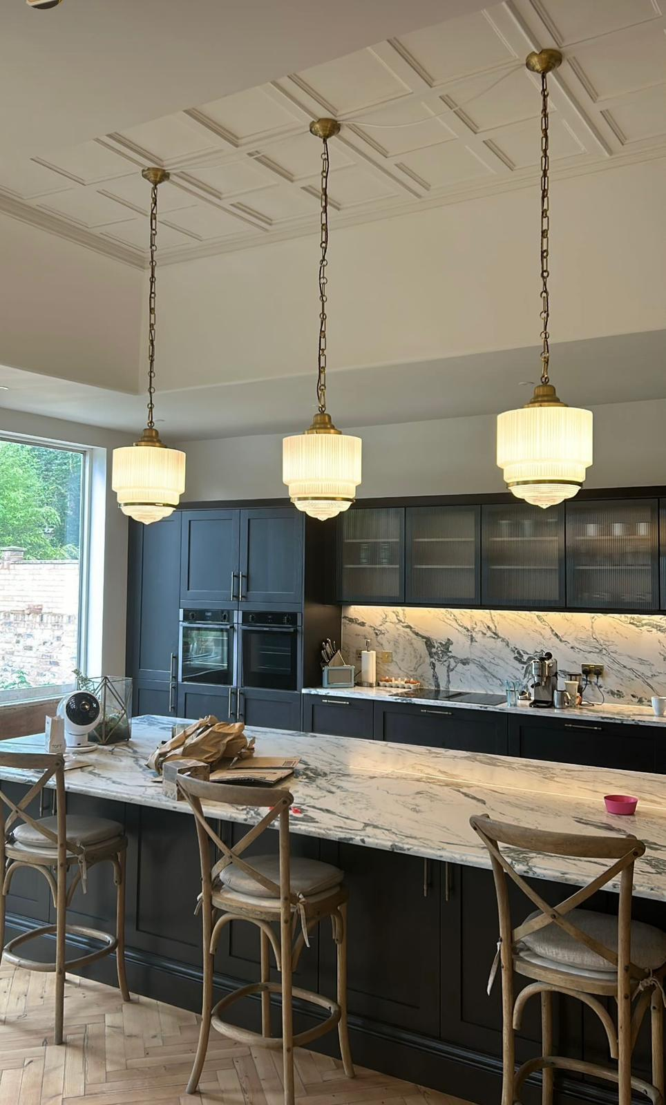 Brass pendant lights installed over marble kitchen island in Cobham